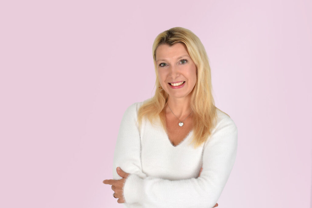 Porträt von Alexandra Groß, Physiotherapeutin und Ernährungsberaterin: in einem weichen weißen Pulli gekleidet blickt sie freundlich in die Kamera; ihre blonden Haare fallen offen über die Schultern nach vorn. 